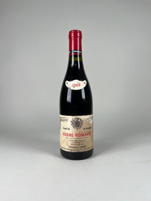 une vieille bouteille de vin posée sur une table blanche