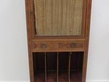 une vieille armoire en bois avec un plateau en osier et une porte vitrée