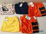 cinq paires de maillots de bain pour garçons sont alignées sur une table