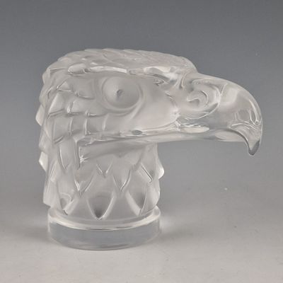 une sculpture en verre représentant une tête d'aigle, posée sur une table