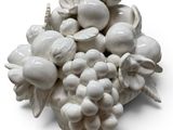 a white figurine of a bunch of grapes on a white surface