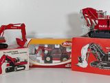 three toy trucks and a box of construction equipment on a table