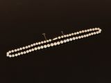 a single strand of pearl beads on a black surface