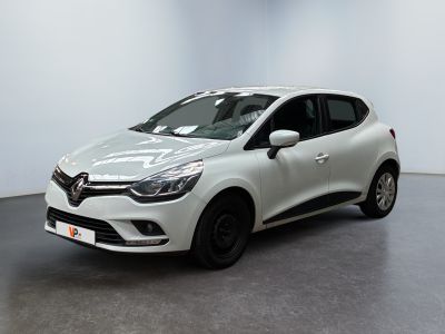 Une voiture blanche est garée dans une pièce au sol noir.