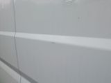 the side of a white van with a hole in the side of it