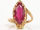 gros plan d'une bague en or avec une pierre rose