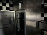 cuisine faiblement éclairée, équipée d'appareils électroménagers en inox et dont les murs sont recouverts d'un motif à carreaux