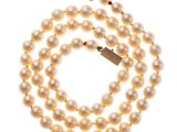 un collier de perles blanches avec un fermoir en or