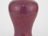 un vase violet reposant sur un socle en bois, sur fond blanc