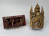 two gold figurines sitting next to each other on a white surface