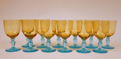 six verres à vin bleus et jaunes sont alignés sur une surface blanche
