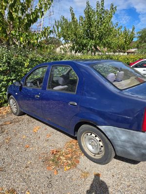 une voiture bleue garée sur un parking, à côté d'un buisson