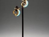 a pair of gold and enamel hoop earrings on a black stand