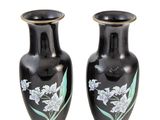 une paire de vases noirs ornés de fleurs peintes sur fond blanc