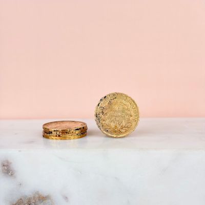 a close up of two gold coins sitting on top of a marble counter