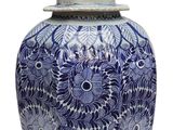 a blue and white vase with a bird on top of it
