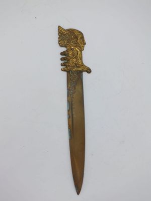 une image représentant un couteau de couleur dorée orné d'une tête de lion