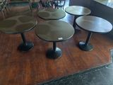 trois tables et quatre tabourets posés sur un parquet dans un restaurant