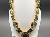 un ensemble collier et boucles d'oreilles vert et or posé sur un mannequin