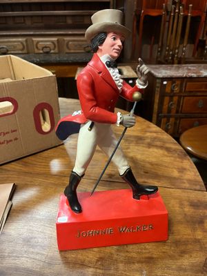 une figurine représentant un homme vêtu d'une veste rouge et d'un chapeau, posée sur une table