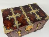 a wooden box with gold decorations on it on a white surface