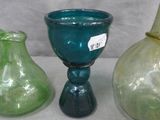 three different colored glass vases on a table