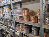 des étagères remplies de différentes sortes de peinture et d'autres articles dans une pièce