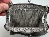 someone is holding a silver purse with a chain around it