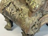 a bronze statue of a woman sitting on top of a chair