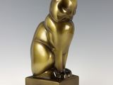 an image of a bronze cat statue sitting on top of a wooden block