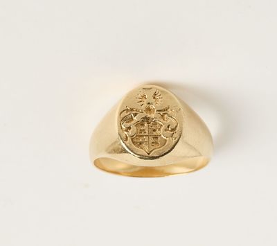 un gros plan d'une chevalière en or ornée d'un blason