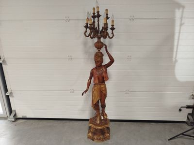 a statue of a man holding a chandelier in a garage