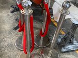 three silver pedestals with red rope on them in a room