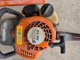 an orange and black chainsaw sitting on the ground next to a piece of wood
