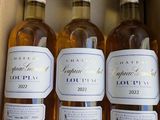 trois bouteilles de vin blanc dans un carton, avec des étiquettes dessus