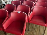 several red chairs are lined up in a row on a wooden floor