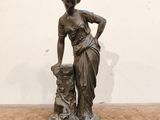 statue en bronze représentant une femme accompagnée d'un chien, posée sur un socle