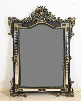 an ornate black and gold framed mirror on a white wall