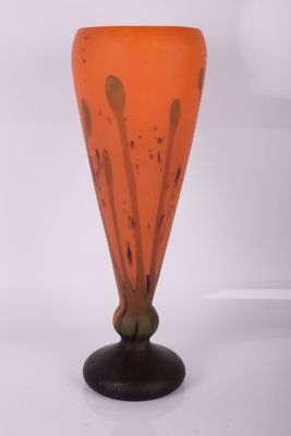 un vase en verre orange posé sur un socle noir