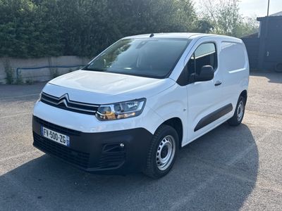 la camionnette blanche est garée sur un parking avec des arbres en arrière-plan