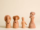 trois figurines en argile représentant des femmes et un homme tenant un panier