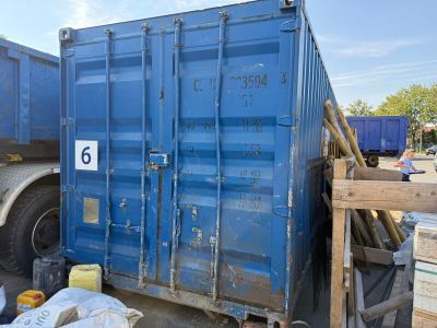 a large blue container sitting on the ground next to a truck
