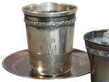 a silver cup and saucer sitting on a saucer
