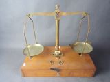 une vieille balance à fléau en laiton, avec un socle en bois et deux plateaux métalliques