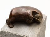 a statue of a cat that is laying on top of a block