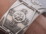 a close up of a silver bracelet on a person ' s arm