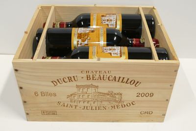 bouteilles de vin dans un coffret en bois sur une surface blanche