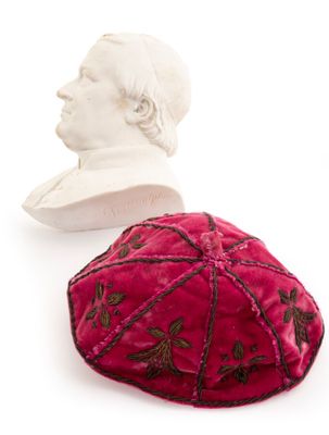 a red velvet kippa with a bust of a man in the background