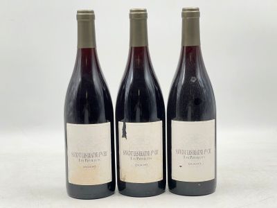 trois bouteilles de vin rouge sont posées sur une surface blanche