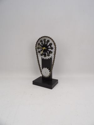 une horloge composée de chaînes et d'engrenages, posée sur un socle